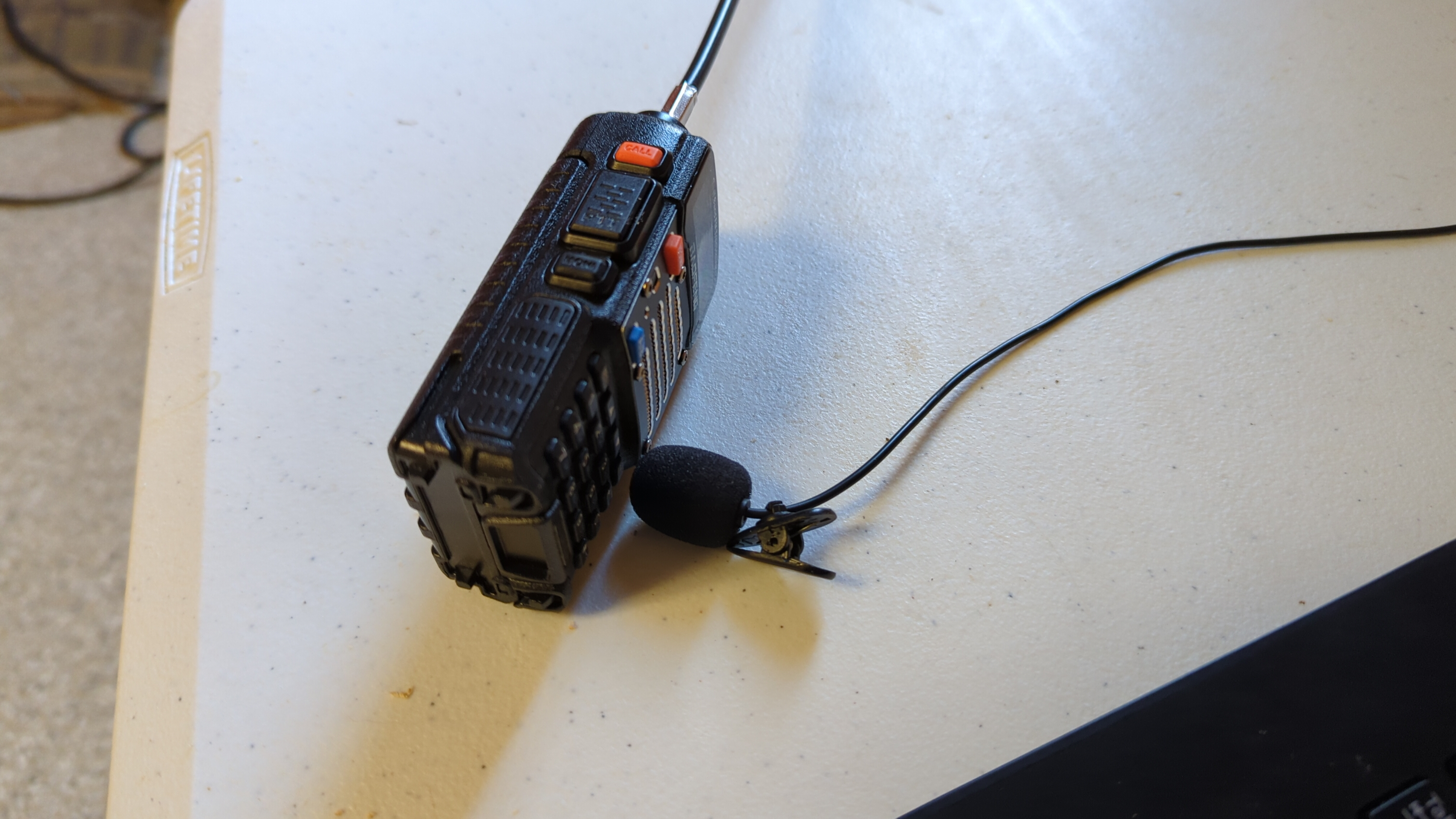 My radio laying on its side on a table with its speaker pointing to a clip-on lav mic