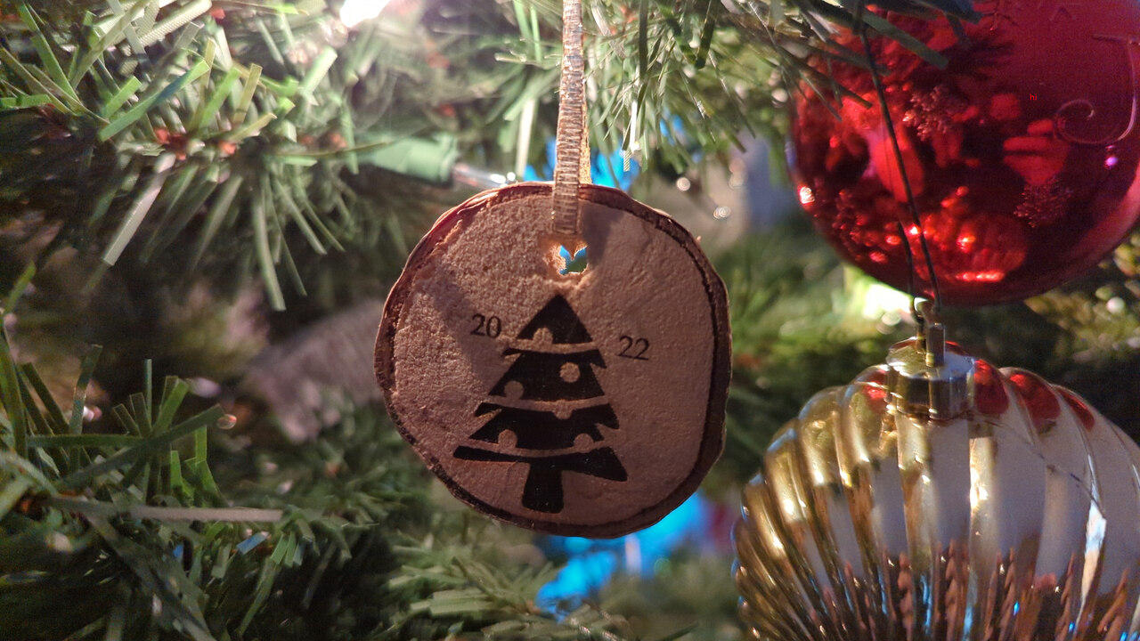 A finished ornament hanging from the branch of a Christmas tree