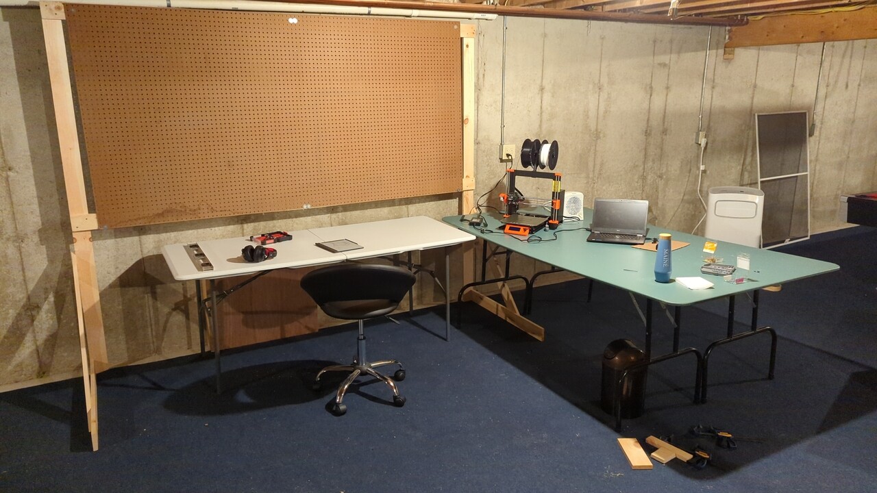 Pegboard frame fully assembled and installed behind a table with the pegboard sheet on the front