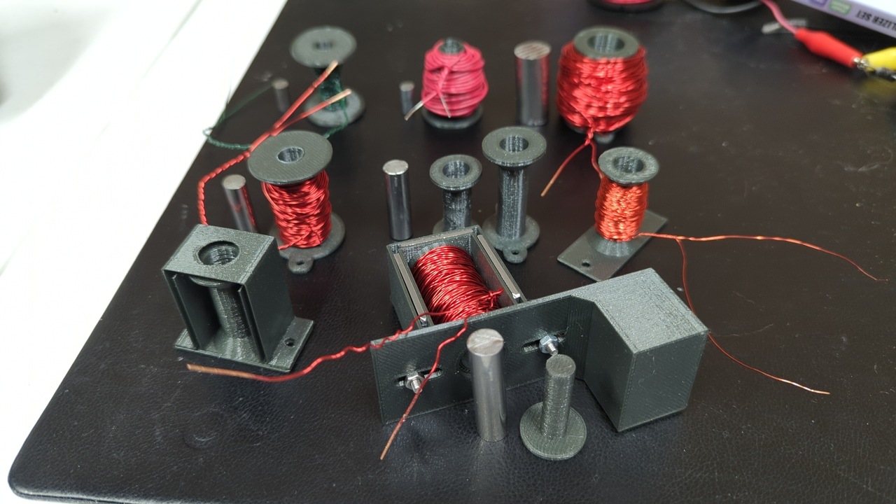 About a dozen iterations of the solenoid actuator in different sizes and wire gauges, along with several plungers