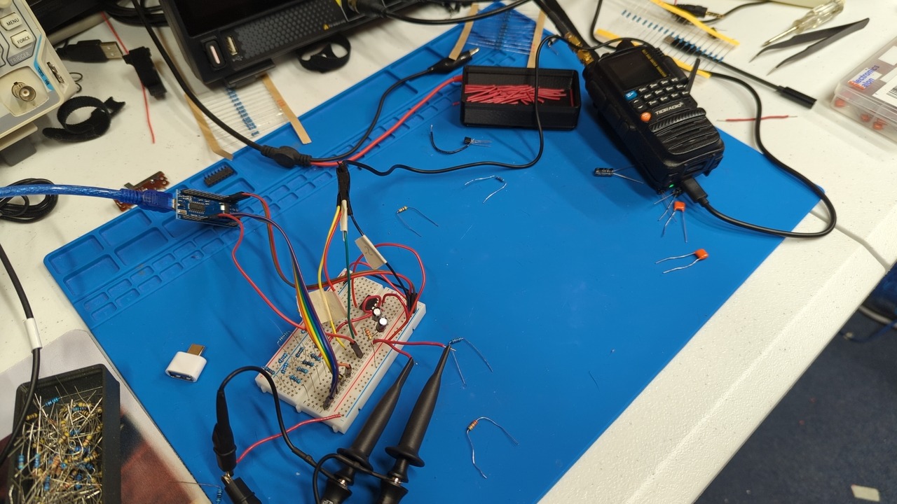 Breadboard with various components, wires, and scope probes on a blue silicone mat. One of the cables is connected to the audio connector of my handheld transceiver.