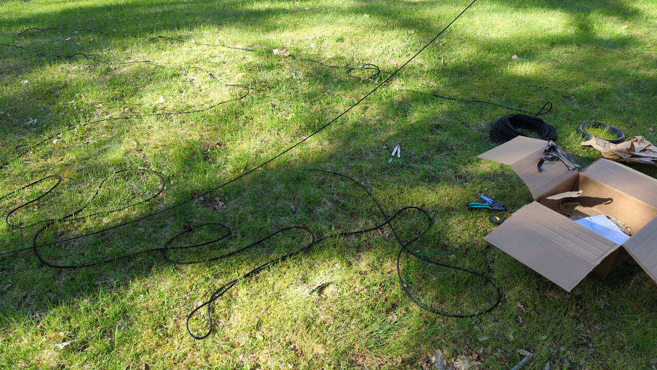 Rope, tools, and an open cardboard box of parts on the grass as the sun goes down