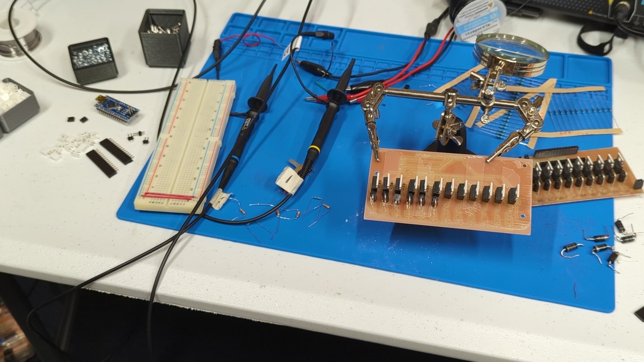 A partially assembled octave module PCB held by a third hand clamp. Various components sit waiting for their turn to be soldered on.
