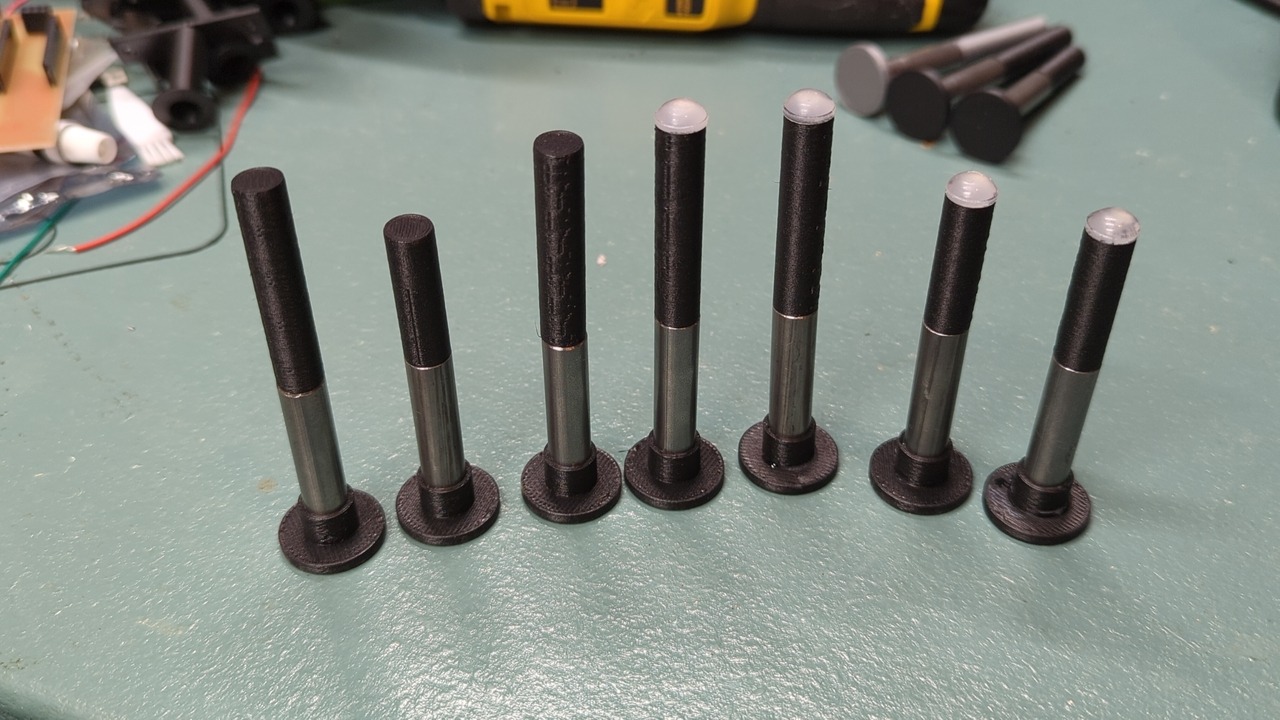 Seven plungers of the new design standing upside down on a table. Three of the plungers are missing their silicone feet.