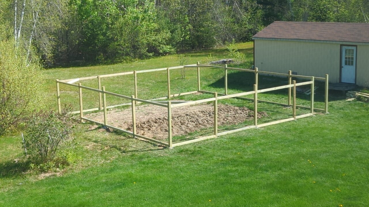 The partially completed fence with posts, rails, and corner braces installed