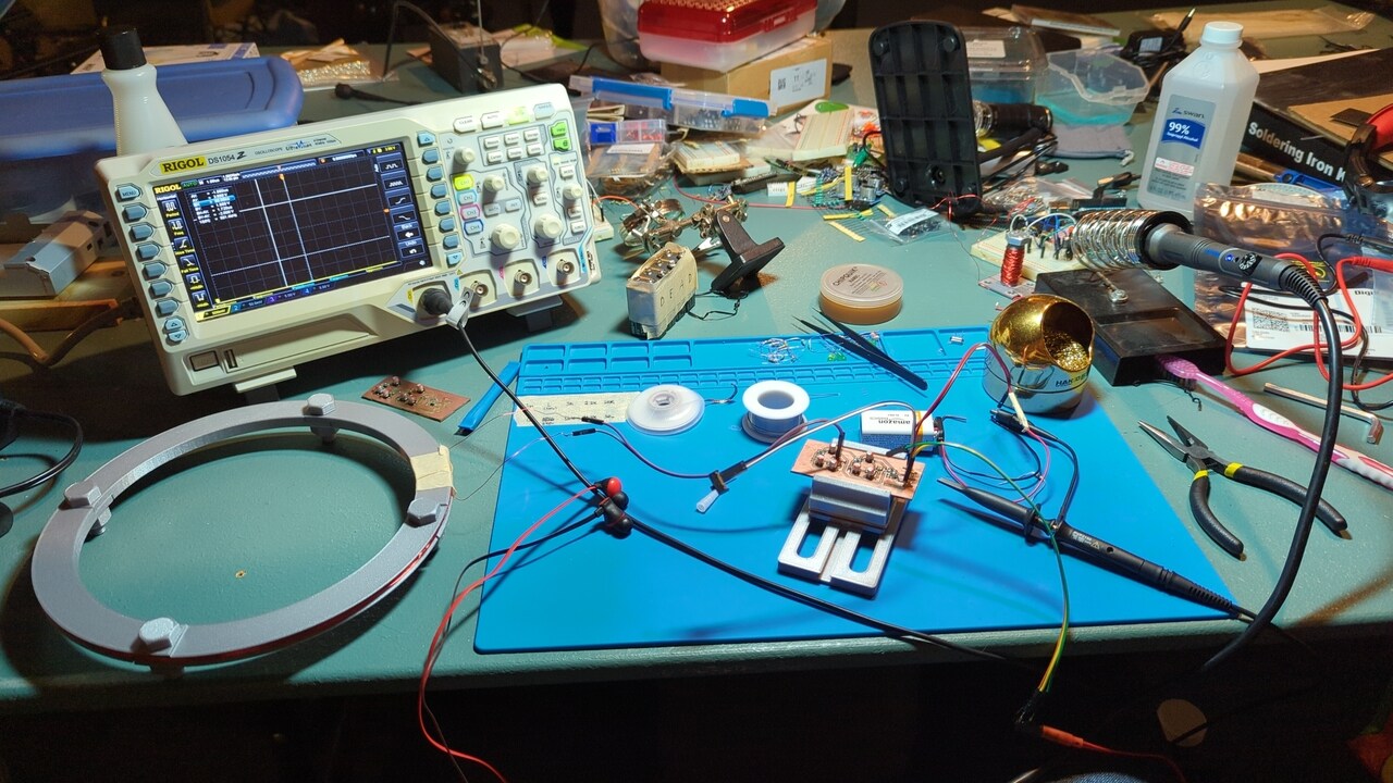 My lab bench showing the metal detector circuit, coil, battery, oscilloscope, and lots and lots of other stuff