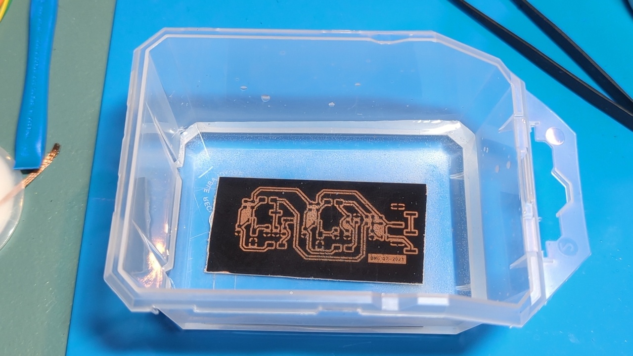 PCB submerged in etchant in a small container
