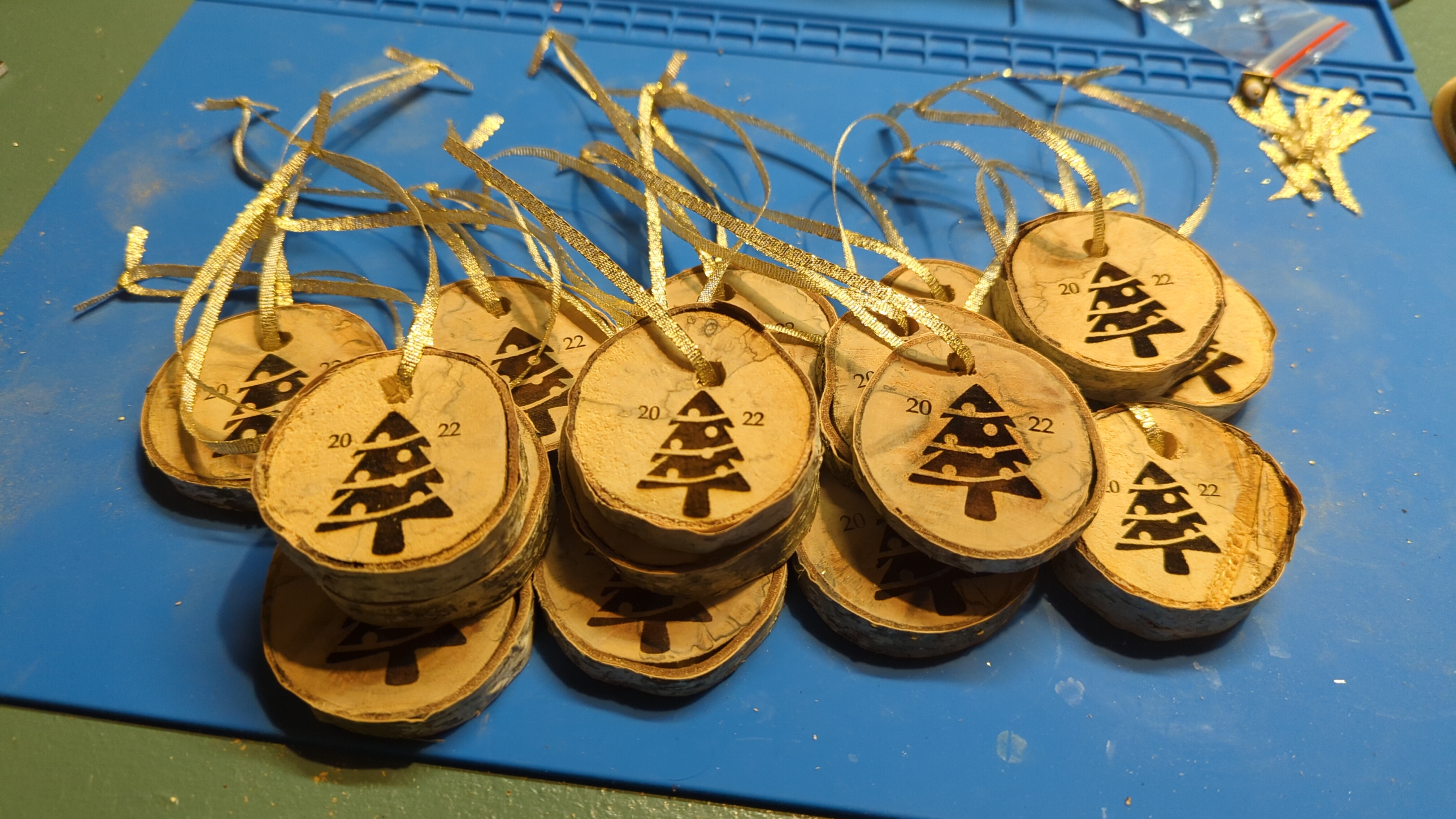 A pile of custom birch Christmas ornaments with trees and the current year etched onto them